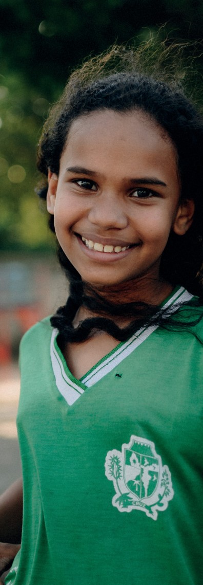Adolescente, menina, indÃ­gena/negra sorri para cÃ¢mera usando uniforme da escola