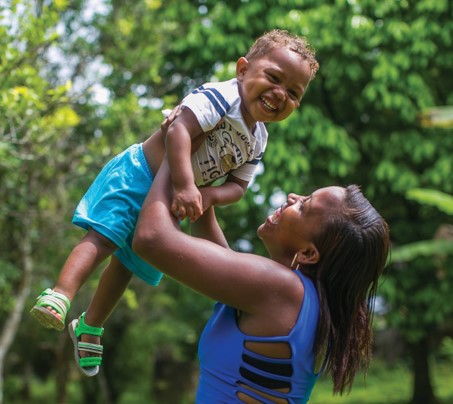 MÃ£e segura bebÃª no alto, ambos sorriem 