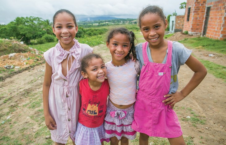 Quatro meninas se abraÃ§am e sorriem 