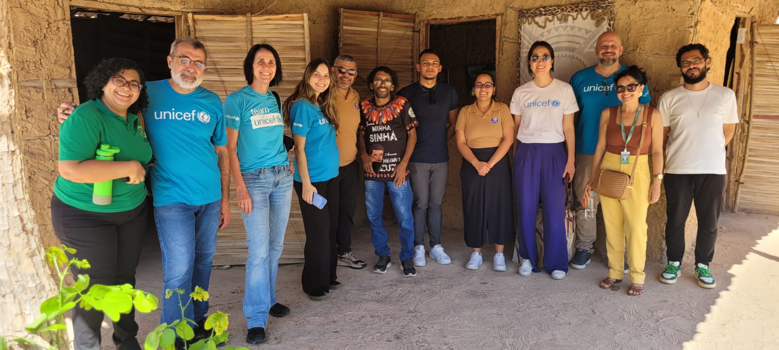 Grupo do Unicef e parceiros pousam para fotografia em uma casa de barro