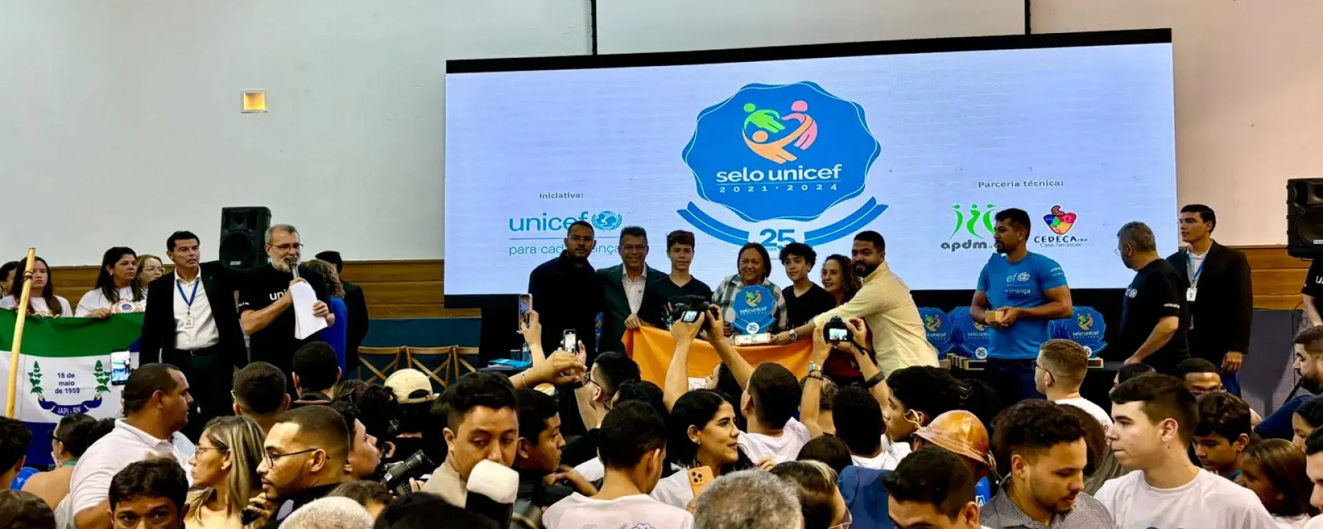 Municípios do Rio Grande do Norte celebram a certificação do Selo UNICEF. No palco, a governadora Fátima Bezerra entrega o troféu a representantes municipais