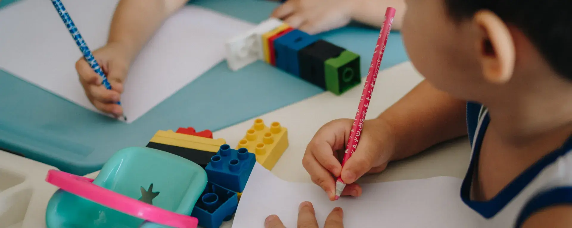 Duas crianças pequenas com lápis e papel desenhando
