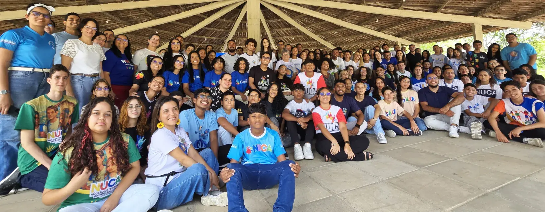 grupo de adolescentes estão reunidos e uma estrutura circular e de madeira