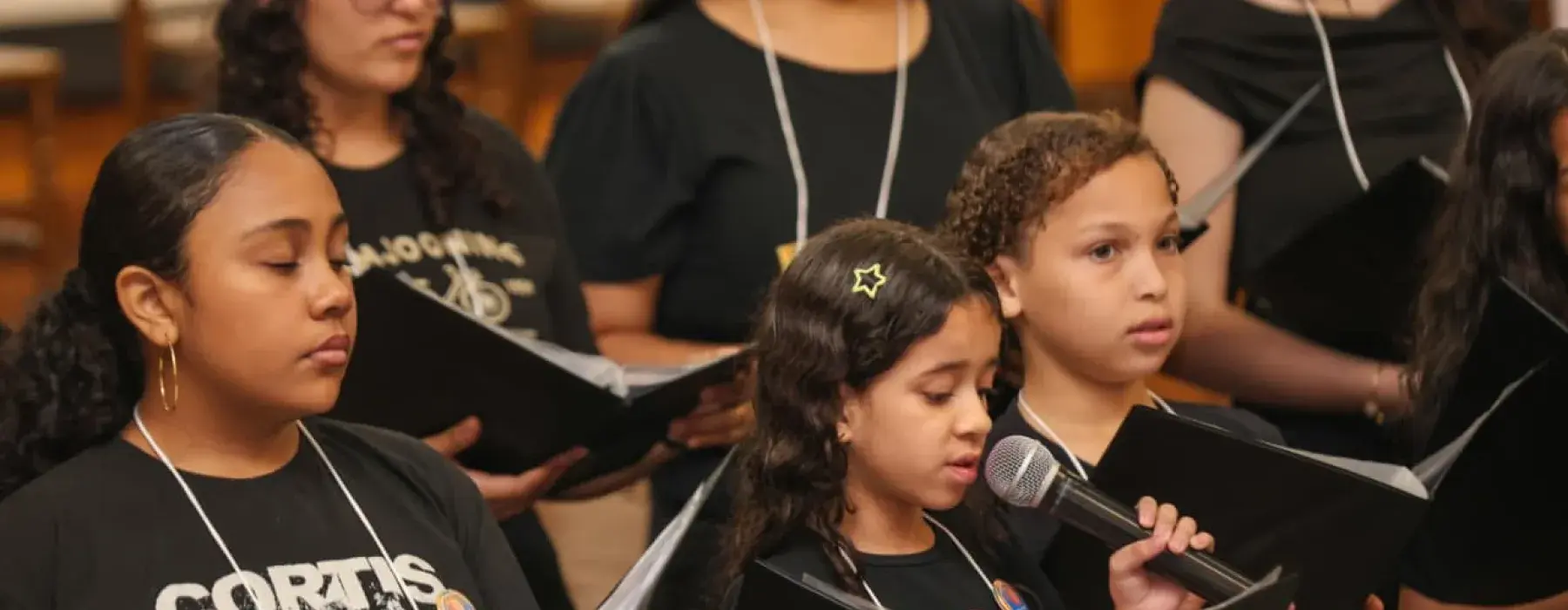 grupo de meninas cantam com partitura 
