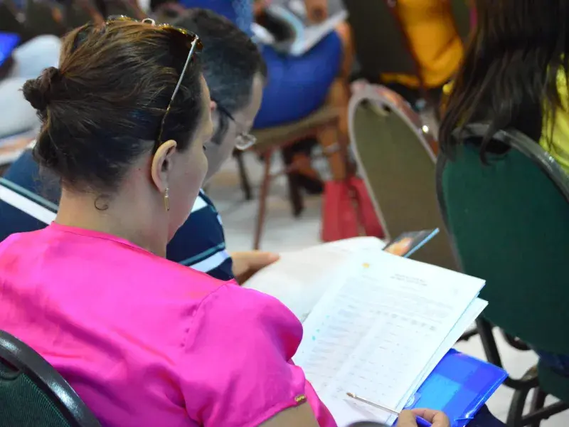 Um homem e uma mulher, de costas, olham para um papel no Ciclo de Capacitação do Selo UNICEF 2018, em Teresina