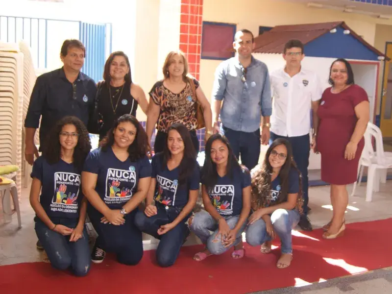 Pessoas posam para a foto - entre elas há adolescentes com uma camisa na qual está escrito NUCA e adultos