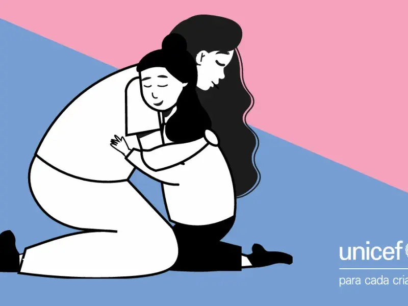 Em desenho, uma mulher adulta abraça uma criança, ao fundo logo do UNICEF