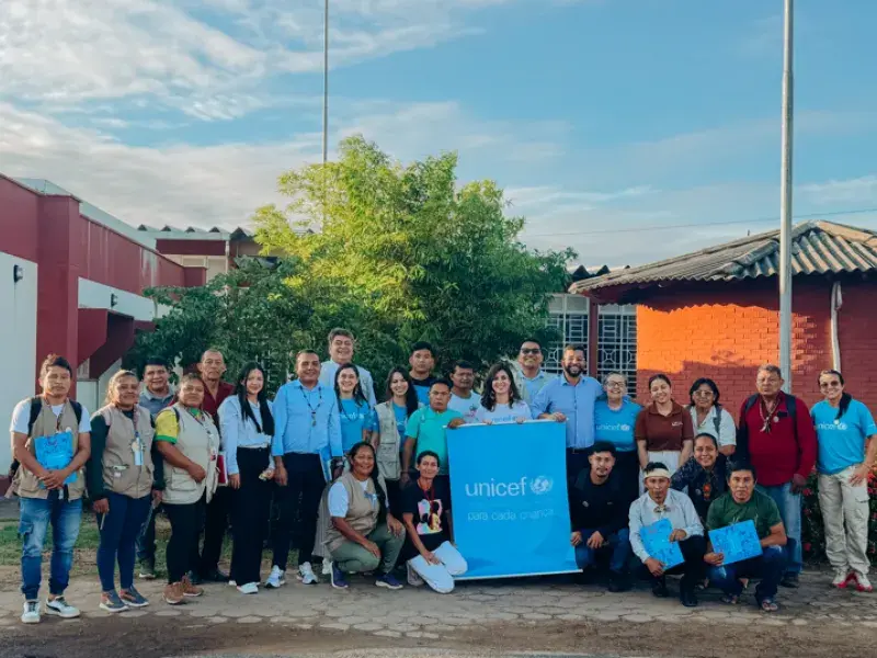 organizações indígenas e profissionais do UNICEF pousam para a foto ao ar livre com o logo do UNICEF