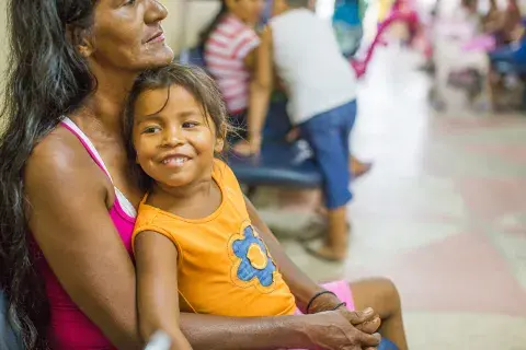 Uma menina sorri no colo de sua mãe