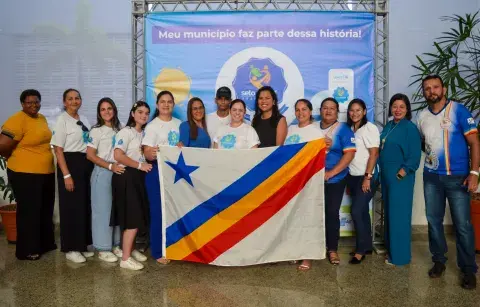 Grupo de pessoas seguram a bandeira do estado de Rôndonia, ao fundo banner do Selo UNICEF