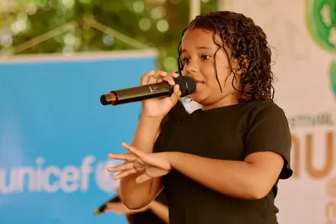 A frente do banner azul do UNICEF, adolescente do NUCA se expressa