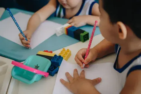 Duas crianças pequenas com lápis e papel desenhando