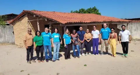 Grupo do UNICEF pousa para foto ao lado de uma casa de barro