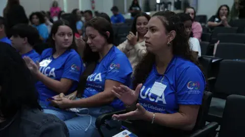Jovens sentadas em auditório