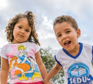 uma menina e um menino, cerca de 5 anos, sorriem para a câmera 