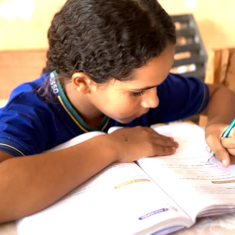 Adolescente negra fardada escrevendo em um livro