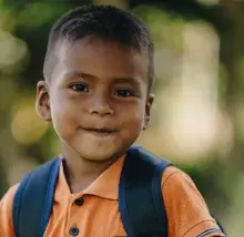 menino sorrindo com mochila nas costas